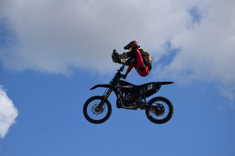 Freestyle jump on a dirt bike with a pink and blue graphics kit