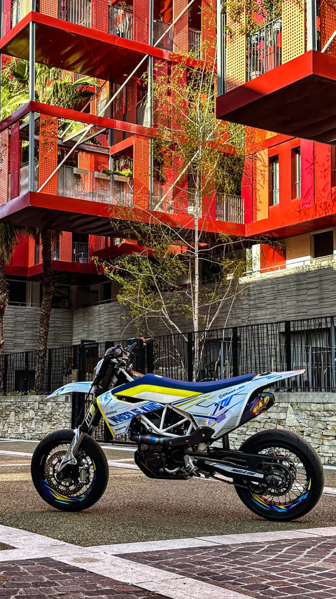 Supermotard bleu et jaune devant une façade rouge