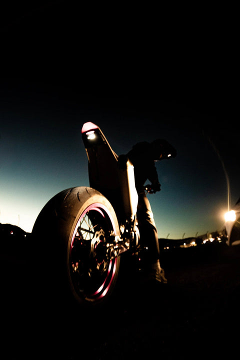 Silhouette d’une moto sur sa roue arrière dans une lumière nocturne