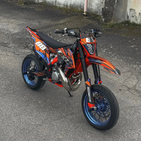 Moto naranja con kit de adhesivos multicolor en un patio