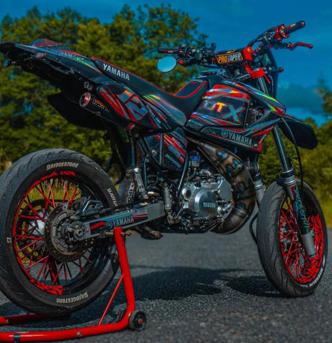 Supermotard noir, rouge et bleu posé sur une béquille d’atelier