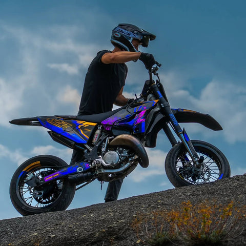 Motard à côté d’un supermotard bleu sur un promontoire rocheux