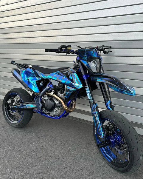 Supermotard bleu et noir devant une porte de garage