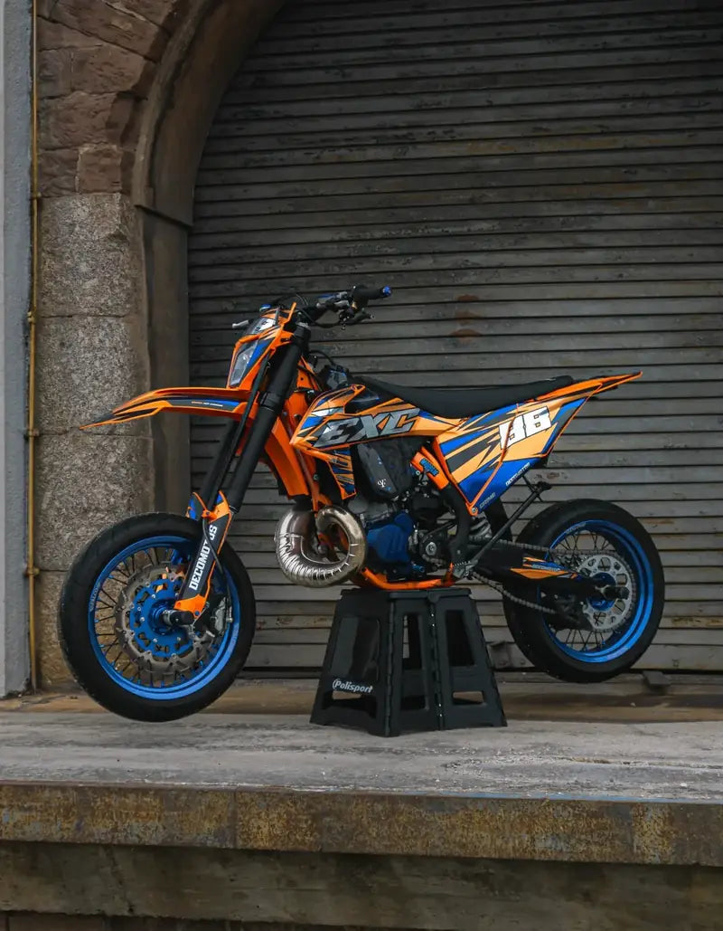 Supermotard con kit de adhesivos naranja y azul en impresión cromada y acabado brillante, sobre su caballete