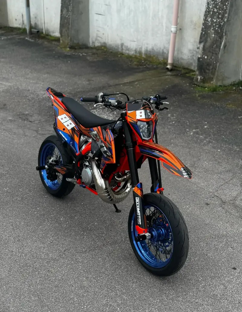 El mismo kit de adhesivos naranja y azul en impresión cromada y acabado brillante, visto de tres cuartos