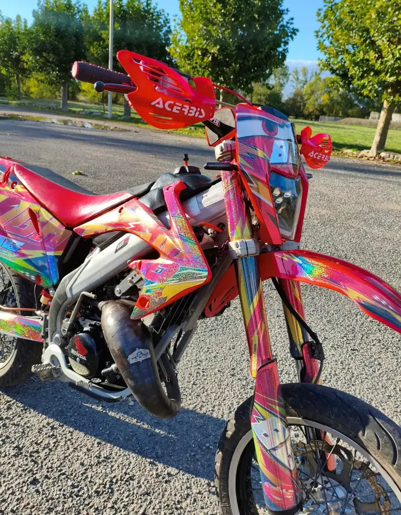Supermotard rosa y roja con acabado Súper purpurina, la purpurina brilla al sol en la placa del faro, las aletas y la horquilla